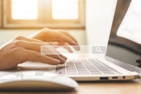 Hands typing a search on a laptop